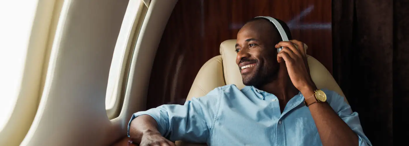 Smiling man on plane wearing noise cancelling headphones